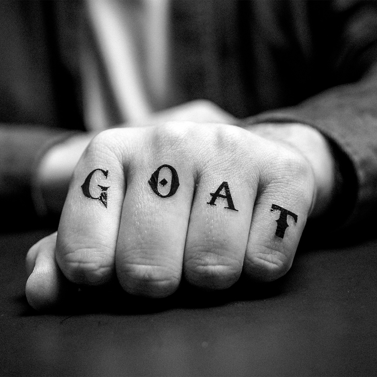 Black and white photo of a clenched hand with the word “GOAT” written across the knuckles in a temporary tattoo.
