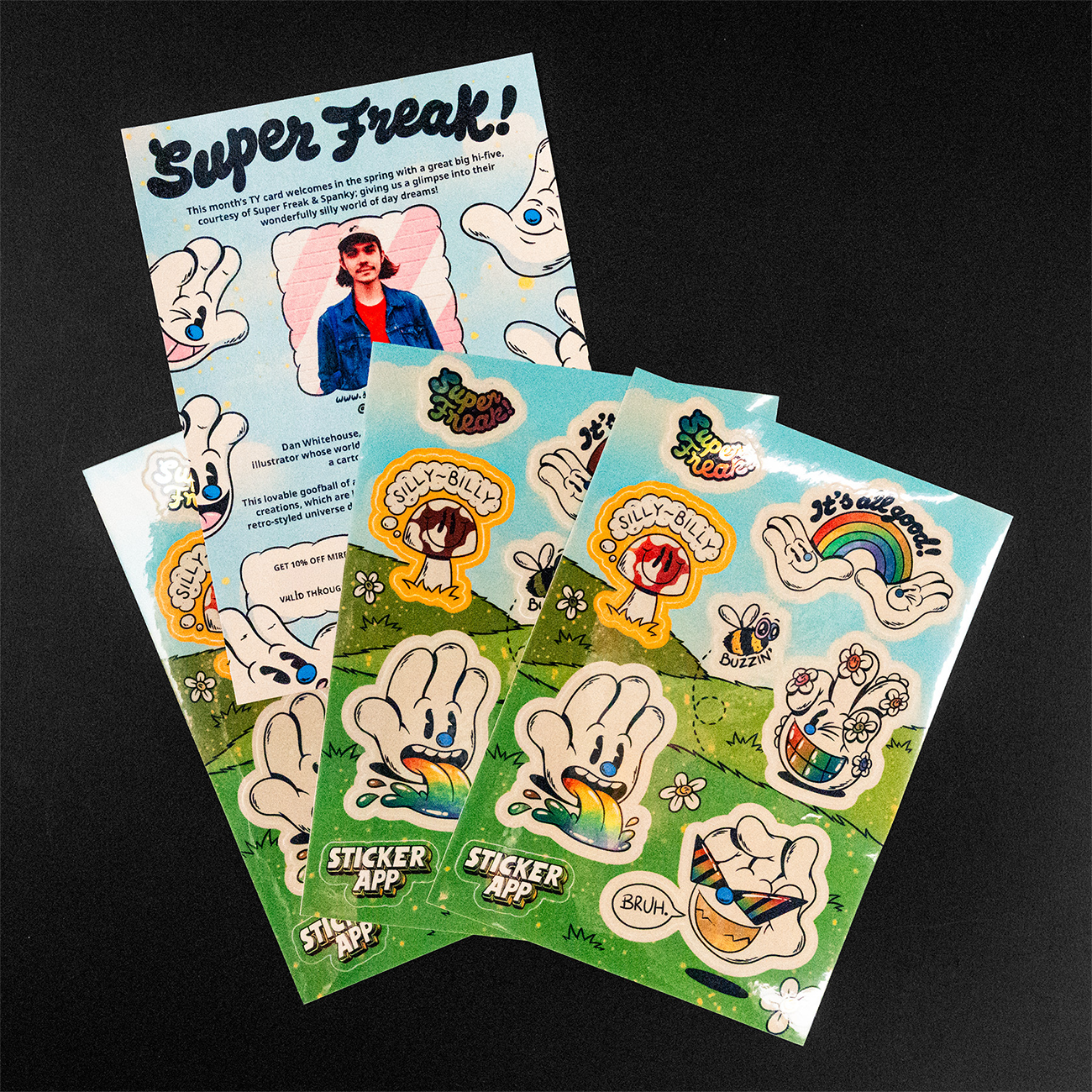 Colorful sticker sheets featuring cartoon hands, rainbows, and cheerful characters on a grassy background, with a leaflet titled "Super Freak!"