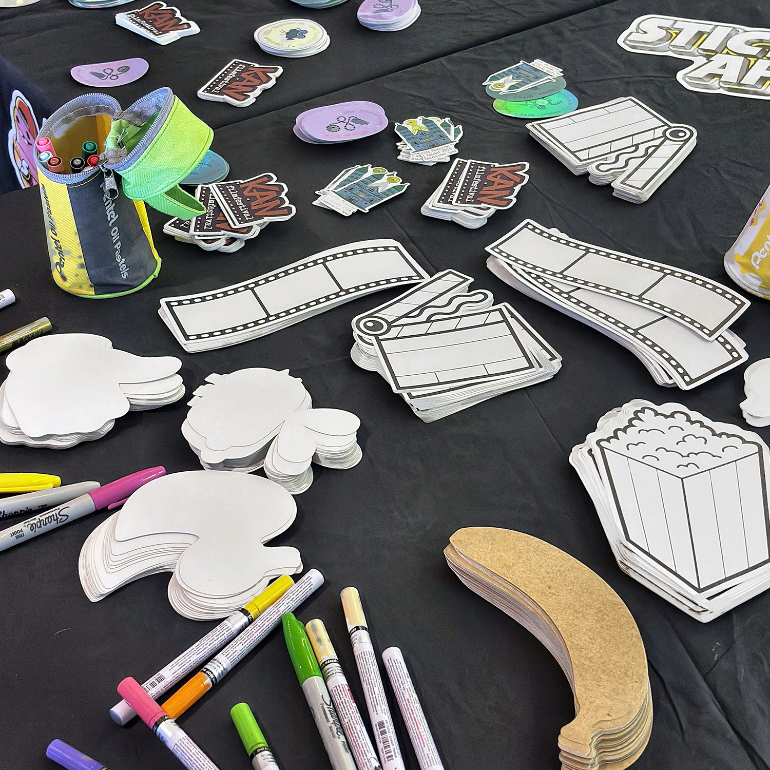 Sticker-Bastelstation beim KAN Film Festival mit leeren Freiform-Stickern in Form von Popcorn, Filmstreifen und Filmklappen, Kraftpapier-Aufklebern und Lackstiften