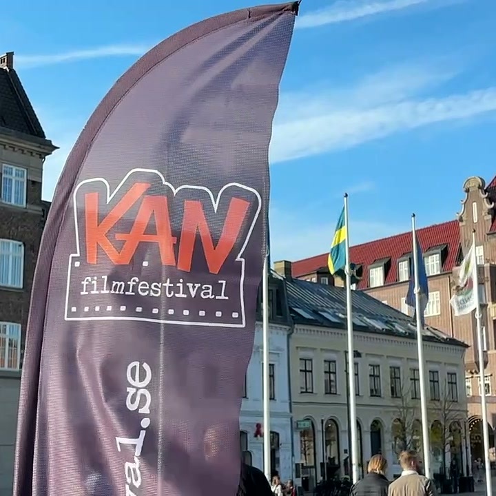 Beachflag vom KAN Film Festival vor historischen Gebäuden und Fahnen auf einem Platz in Lund